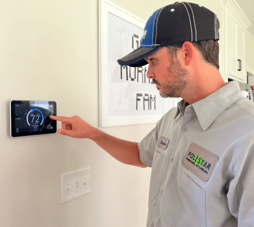 HVAC technician installing a smart thermostat on the wall.