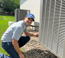 HVAC technician repairing an air conditioning unit outdoors.