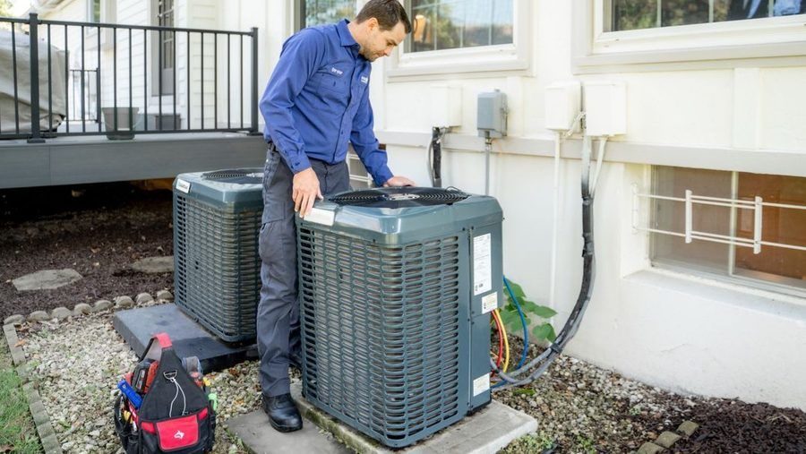 Polestar technician standing above HVAC unit after AC replacement.