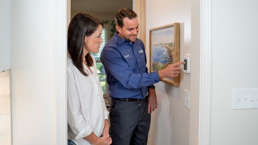 Polestar tech showing client the thermostat after installing ductless mini split.