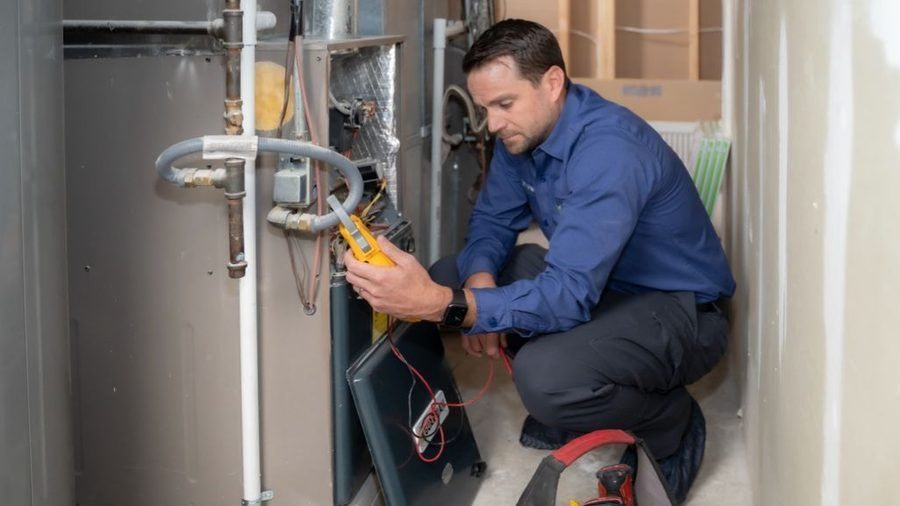 HVAC technician in front of heating unit inspecting.
